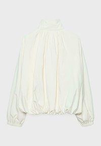 Blouse crème à manches longues avec col haut, tissu froncé aux épaules, poignets élastiques et ourlet élastique pour une coupe ample et bouffante.