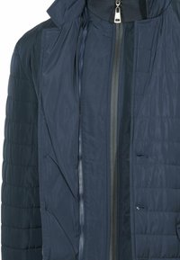 Giacca puffer navy, texture trapuntata, chiusura frontale con zip e due aperture, interni con fodera liscia, colletto alla moda e dettagli a coste.