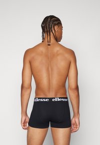 Black boxer briefs with a white elastic waistband featuring the brand logo. The fabric is smooth, and the fit is snug.