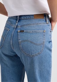 Lichtblauwe denim jeans met een klassiek ontwerp van vijf zakken, voorzien van een leren label aan de tailleband en contrasterende stiksels.