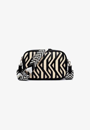 Sac bandoulière rectangulaire avec texture beige tissée et motifs géométriques noirs audacieux, doté d'une large bandoulière réglable en chevron noir et blanc.