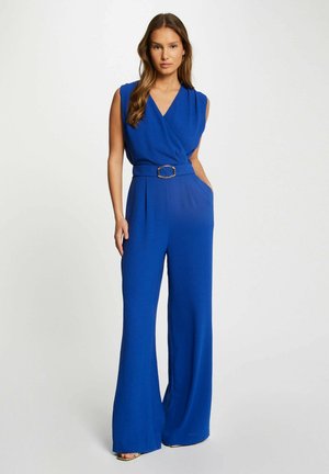 Koninklijk blauwe jumpsuit met een wikkelnek, mouwloos ontwerp, brede pijpen, riem met zilveren hardware en zijzakken.