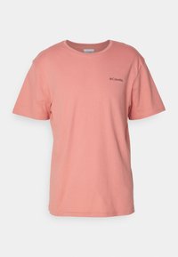 Ljusrosa bomullströja med rund halsringning och korta ärmar. Har en liten svart Columbia-logotyp på vänster bröst.