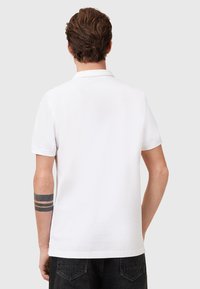 Witte polo met korte mouwen, een klassieke kraag en een gladde katoenstructuur. Eenvoudig ontwerp zonder zichtbare patronen of accenten.