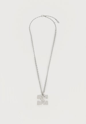 Ασημένιο κολιέ με αλυσίδα και τετράγωνο μενταγιόν που έχει κοπτή σχεδίαση με σύμβολο δολαρίου, παρουσιάζεται σε λευκό φόντο.