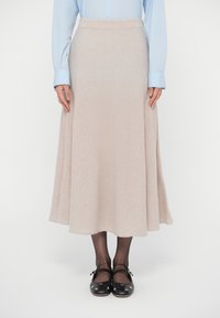 Beige, polvipituinen hame, valmistettu pehmeästä kankaasta, jossa liehuva malli. Yhdistetty vaaleansiniseen paitaan ja mustiin kenkiin, joissa hopeanväriset niitit.