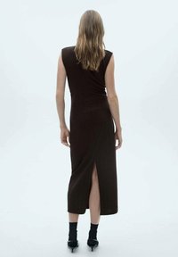 Rochie maro fără mâneci, cu o fanta în spate, realizată dintr-un material moale. Are un design ajustat și se termină la jumătatea gambei.