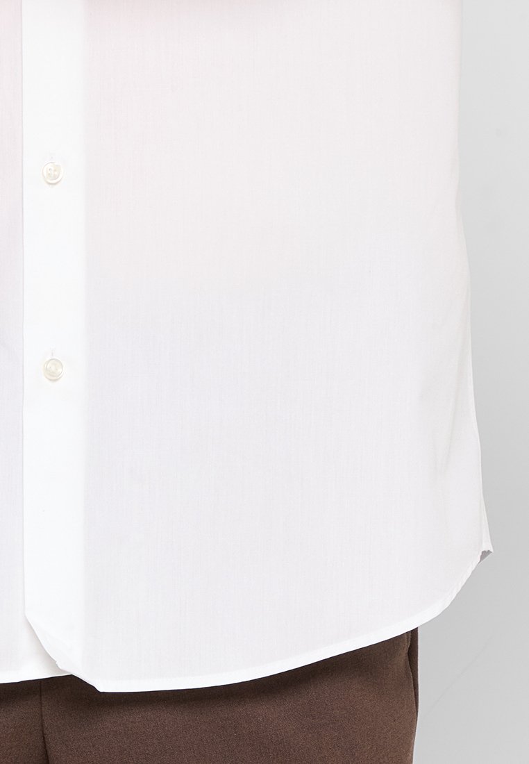 Chemise en coton blanc avec une texture lisse, fermeture à bouton et ourlet arrondi, associée à un bas en tissu marron.