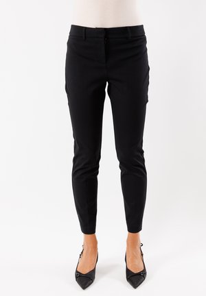 Pantaloni neri su misura realizzati in tessuto morbido, caratterizzati da una vestibilità slim, tasche laterali e una vita a media altezza, abbinati a décolleté neri a punta.