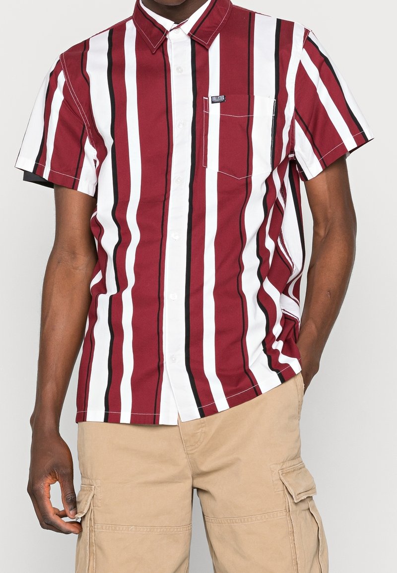 Kurzärmeliges Button-Up-Hemd mit burgunderfarbenen, weißen und schwarzen vertikalen Streifen. Baumwollmaterial mit einer Brusttasche und einem lässigen Kragen.