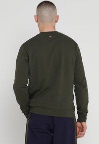 Sweatshirt verde oliva con collo a giro, polsini e orlo a costine, e un piccolo logo sulla parte posteriore del collo, realizzato in tessuto morbido.