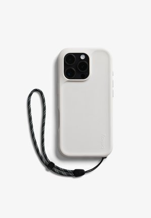 Coque de smartphone blanche avec appareil photo à triple lentille, attachée à une lanière de poignet tressée noire et blanche, sur un fond blanc.