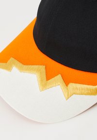 Schwarz-orange Kappe mit einem Zickzack-Goldstickdetails auf der Vorderseite. Aus Stoff gefertigt, präsentiert sie einen gebogenen Schirm und ein strukturiertes Design.