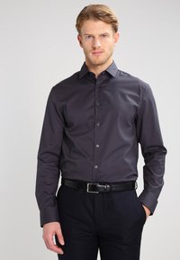 Dark gray long-sleeve shirt with a button-down collar, smooth texture, and front buttons. Paired with a black belt and dark pants.