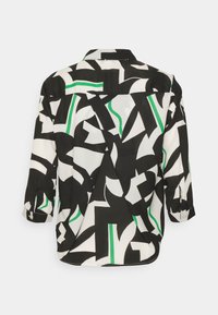 Vue arrière d'une chemise à motifs présentant un contraste de formes noires et blanches avec des accents verts, confectionnée dans un tissu lisse.