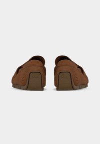 Mocassins en daim marron vus de dos avec semelles en caoutchouc texturé marron, coutures visibles et logo Clarks sur les patchs au talon.