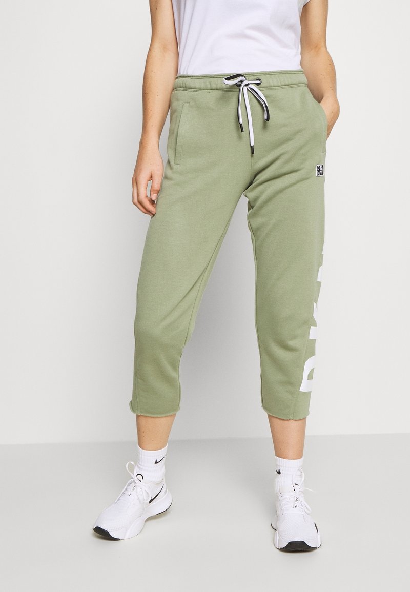 Ljusgröna bomullssweatpants med dragsko i midjan, sidofickor, fållade cuffar och vit logotekst på vänster ben.