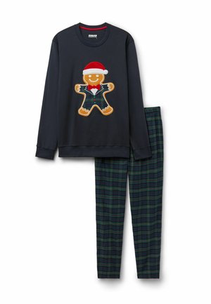 Marineblaues Langarmshirt mit einem Lebkuchenmann, der einen Weihnachtsmann-Hut und einen karierter Anzug trägt, kombiniert mit grünen und marineblauen karrierten Hosen.