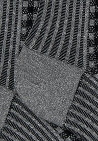 Calzini grigi con vari motivi, tra cui texture rigate e lisce, con accenti metallici e sezioni neri a contrasto.