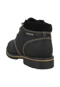 Black leather ankle boot with suede accents, padded collar, and white stitching. Features a rugged rubber sole and embossed logo detail.