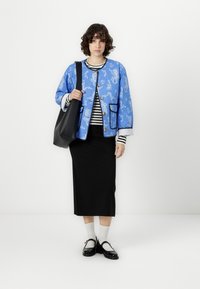Blue patterned lightweight jacket with gold buttons, striped black and white top, black midi skirt, and black shoes with white socks.
