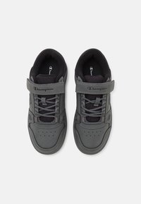 Un paio di sneaker grigie Champion con cinturini in velcro e lacci, con linguette imbottite nere e interno nero, viste dall'alto.