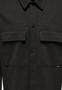 Dark gray button-up shirt made from textured fabric, featuring two chest pockets, black buttons, and a classic collar design.