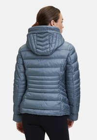 Ljust blå pufferjacka med huva, med kviltad sömnad och en mjuk textur, designad för värme och komfort.