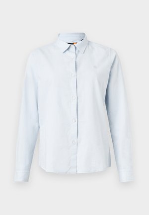 Chemise à manches longues bleu clair avec un col pointu, fermeture à boutons et tissu doux. Présente un petit logo brodé sur la poitrine.