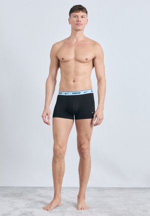 Čierne boxerky s ľahkým modrým opaskom s logom Nike, s tesným strihom a hladkým materiálom, zobrazené na mužskom modeli.