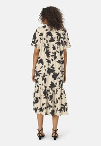 Beiges Midi-Kleid mit schwarzen und burgunderfarbenen Blattmustern. Kurze Ärmel und geraffter, gestufter Saum, aus leichtem Stoff gefertigt.