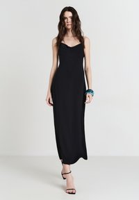 Schwarzes ärmelloses Maxikleid mit einem Wasserfallausschnitt, geradem Schnitt, seitlichen Schlitzen und einer glatten, leichten Textur.