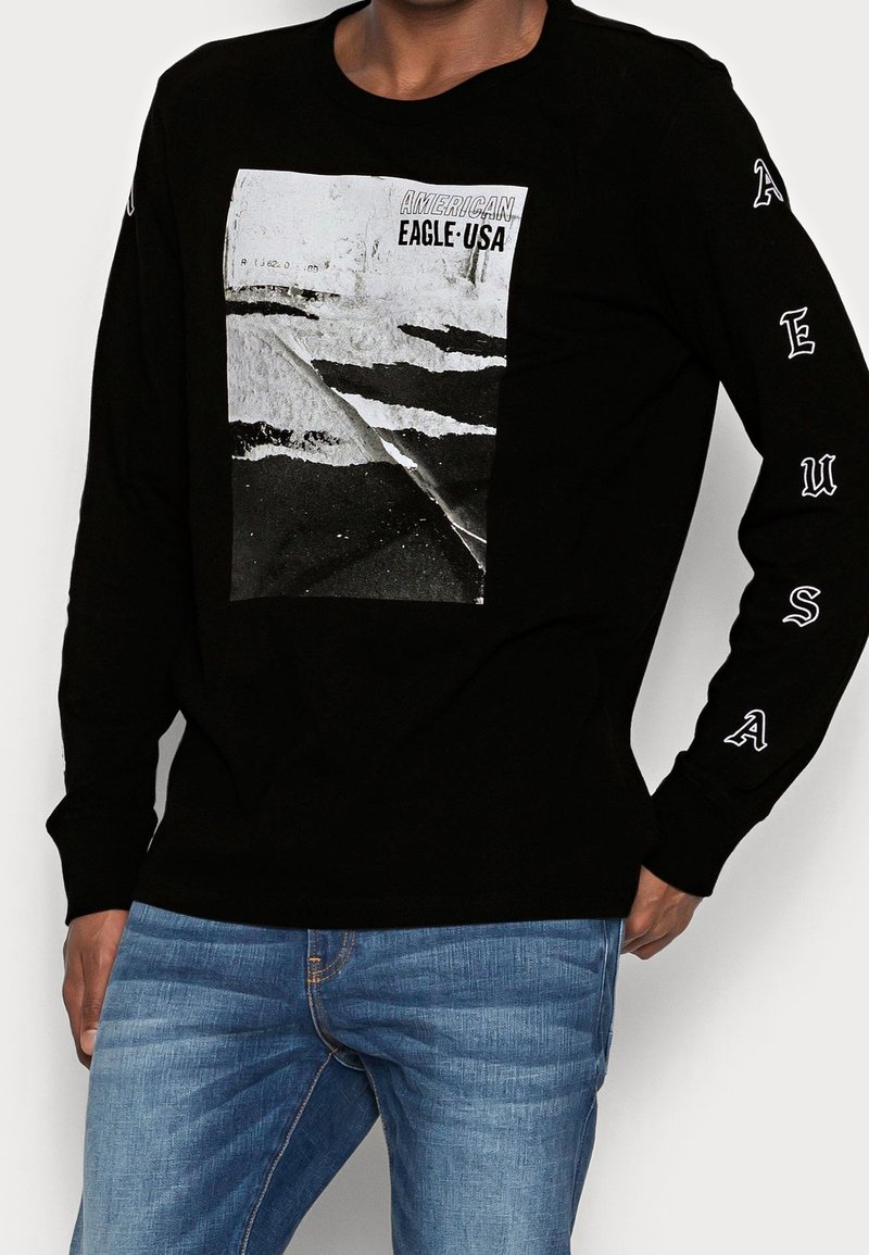 Mustapaita pitkällä hihalla, jossa keskellä on grafiikka tie-tunnelmasta. "EAGLE USA" painettuna hihoihin valkoisella. Pehmeää puuvillakangasta.