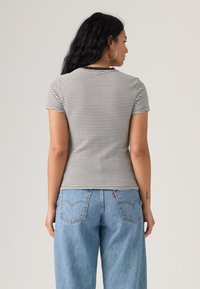 T-shirt rayé à manches courtes, bandes noires et blanches, coupe ajustée, col côtelé, associé à un jean taille haute bleu clair.