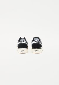 Svart-hvitt mønstrede lavtopp sneakers med semsket skinn-detaljer, gummisåler og logo på hælen, med et teksturert overdesign.