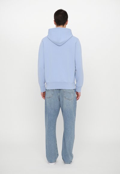 Hoodie azul claro com um capuz espaçoso, punhos e bainha canelados, combinado com jeans azul claro de corte largo com bolsos traseiros.