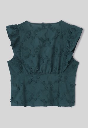 Blouse bleu sarcelle à manches courtes avec manches volantées et motif brodé floral en relief sur tissu lisse, posée à plat sur fond gris.