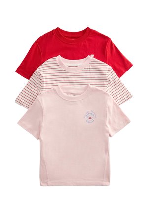 Trzy złożone dziecięce koszulki z krótkim rękawem: jednokolorowa czerwona, biała z cienkimi czerwonymi paskami oraz bladoróżowa z małym wzorem niebieskiej muszli i serca.