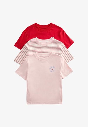 Trzy złożone dziecięce koszulki z krótkim rękawem: jednokolorowa czerwona, biała z cienkimi czerwonymi paskami oraz bladoróżowa z małym wzorem niebieskiej muszli i serca.