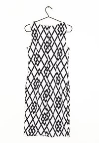 Vestido sin mangas con un patrón geométrico negro sobre un fondo blanco, hecho de tela ligera, exhibido en una percha negra.