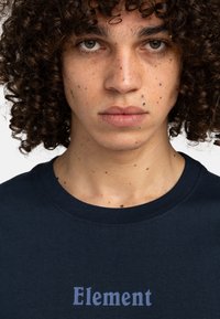 Navyblaue Baumwoll-T-Shirt mit "Element"-Logo in Hellblau, rundem Ausschnitt und kurzen Ärmeln. Weiche Textur mit sichtbaren Nähten.