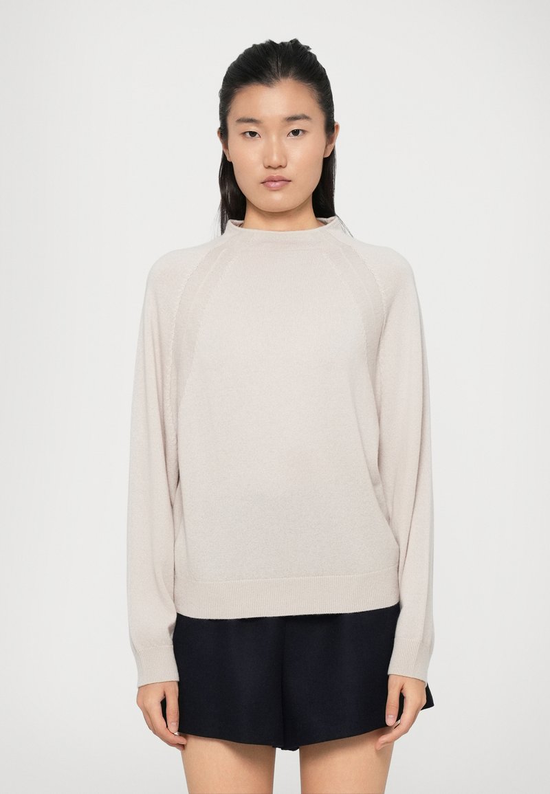 Maglione beige chiaro con collo alto, maniche lunghe e orlo a coste. Texture morbida a maglia, con cuciture raglan per una vestibilità rilassata.