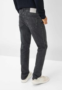 Jeans in denim grigio scuro con taglio dritto, dotati di due tasche posteriori e di una toppa in pelle bianca sulla vita. Texture sottile.