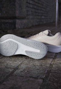 Baskets de sport gris clair avec une tige texturée, une semelle courbée et un motif de traction prononcé sur la semelle extérieure blanche. Conviennent aux activités sportives.