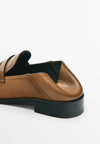 Mocassin en cuir marron avec semelle noire et design à enfiler, présenté de côté et de dos sur un fond blanc.