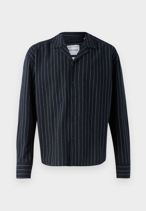 Mornarsko plava košulja s dugim rukavima, dugmadi sprijeda i vertikalnim bijelim i bež prugama, s ovratnikom i ravnim rubom. Mekana tekstura tkanine.