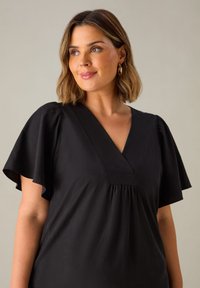 Schwarze Bluse mit kurzen Schmetterlingsärmeln, V-Ausschnitt und gerafftem Detail an der Brust. Hergestellt aus glattem Stoff mit einer weichen Textur.