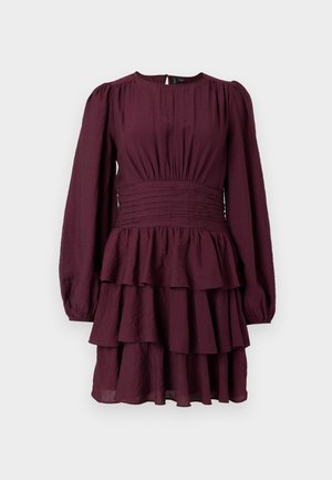 Burgundijska obleka s plastmi, dolgimi napihnjenimi rokavi, nabranim pasom in teksturirano tkanino. Ima draperije na robu.