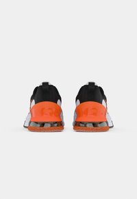 Baskets de sport noires et orange avec un dessus texturé, un talon réfléchissant et une semelle en caoutchouc avec une accent orange et une section transparente.