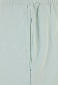 Light green joggers made of ribbed fabric with an elastic waistband and side pockets. Smooth texture with neat stitching details.